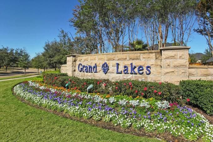 Grand Lakes community entrance monument sign framed by trees and flower beds