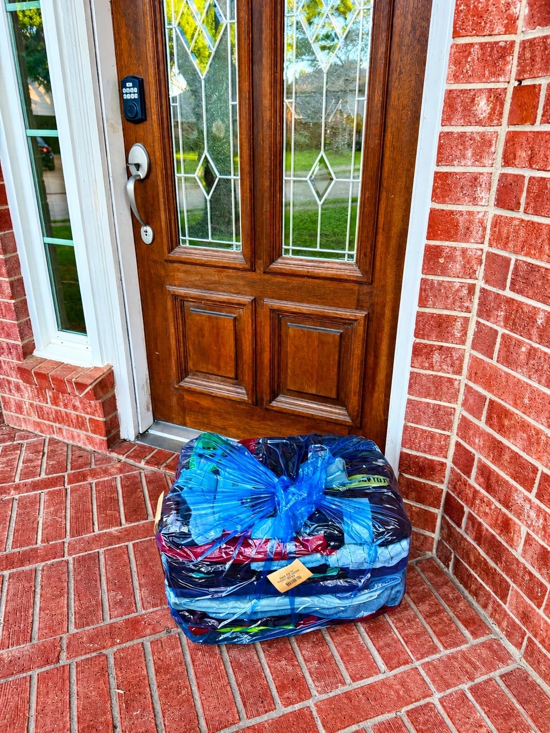 Bagged laundry and a laundry basket staged for pickup on a porch