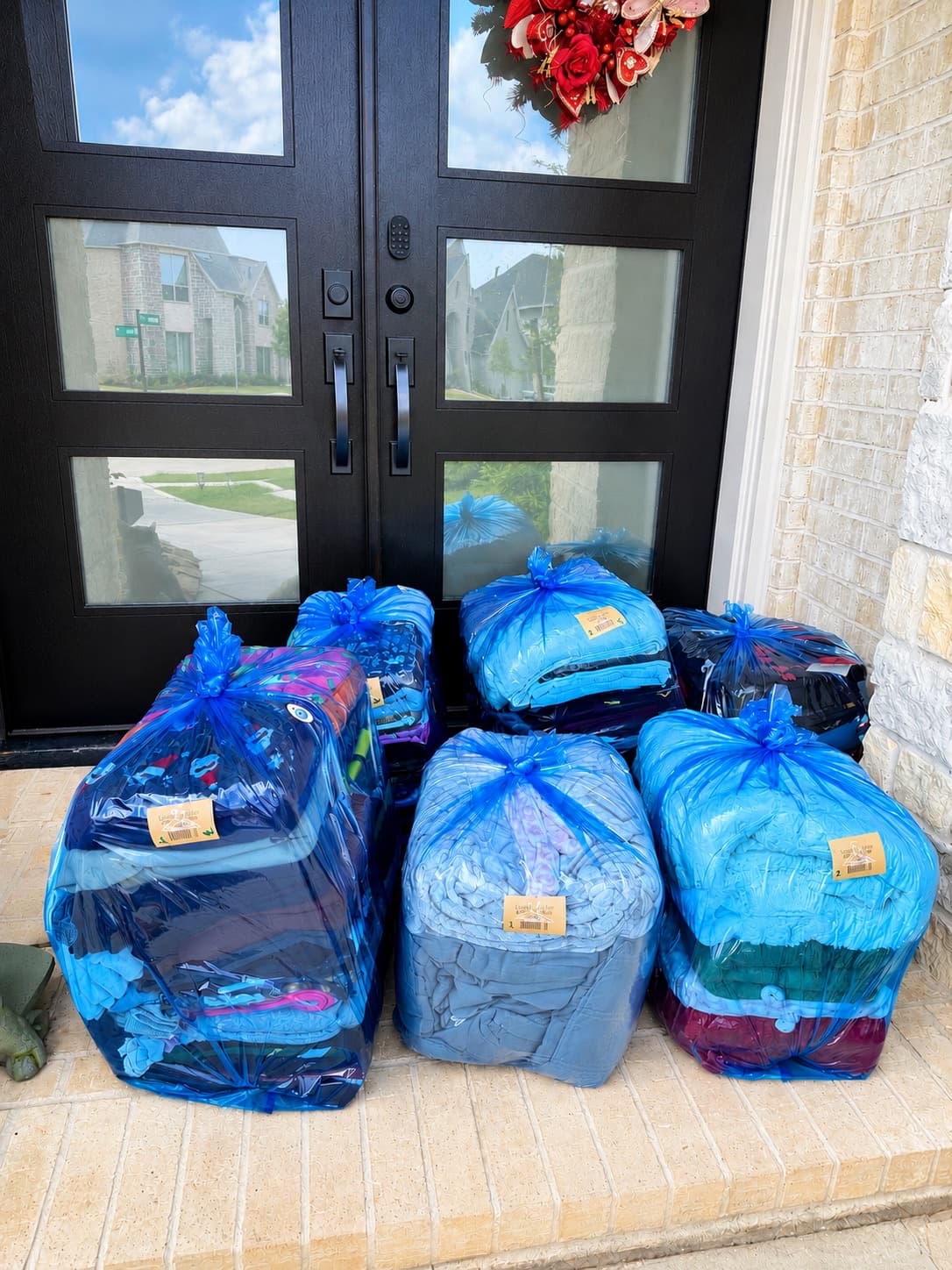 Six bags of laundry ready for pickup at a front entryway with double doors