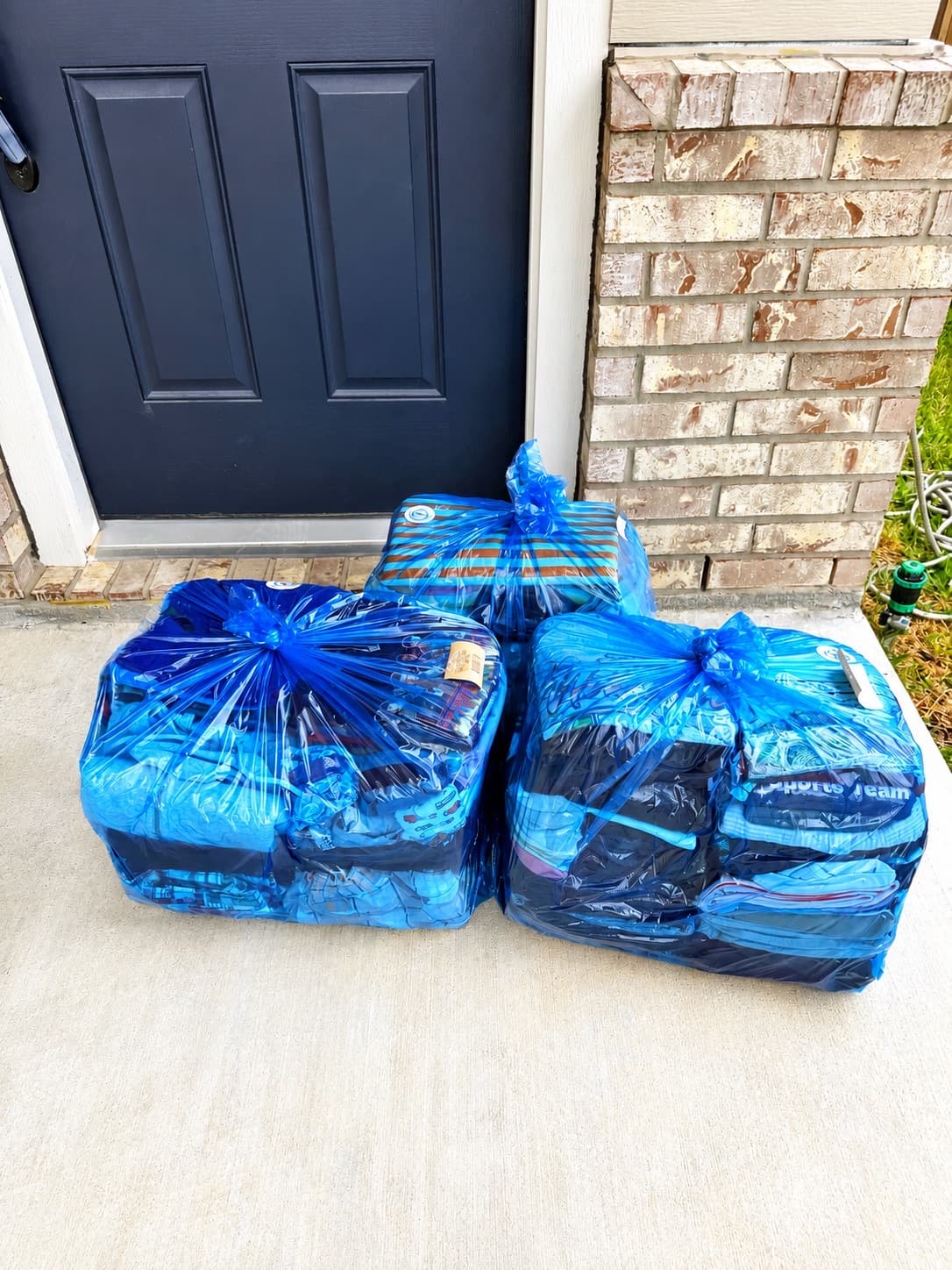 Bagged laundry ready for pickup at a brick home front door