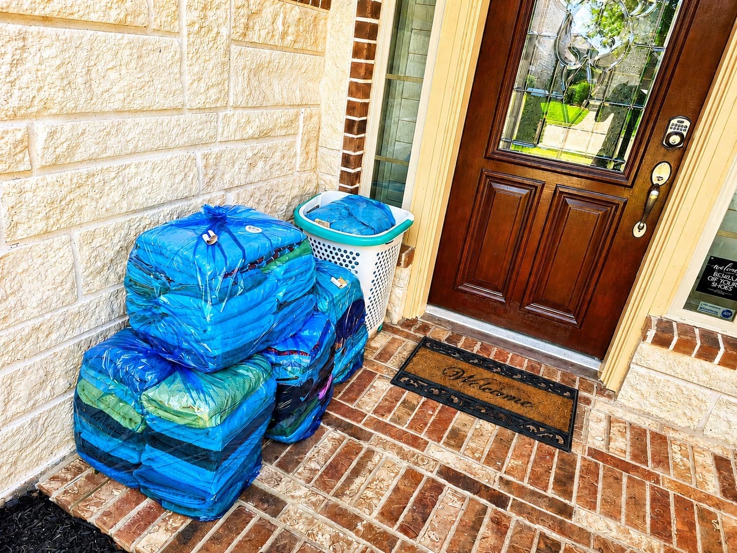 Three bags of laundry ready for pickup at a navy front door