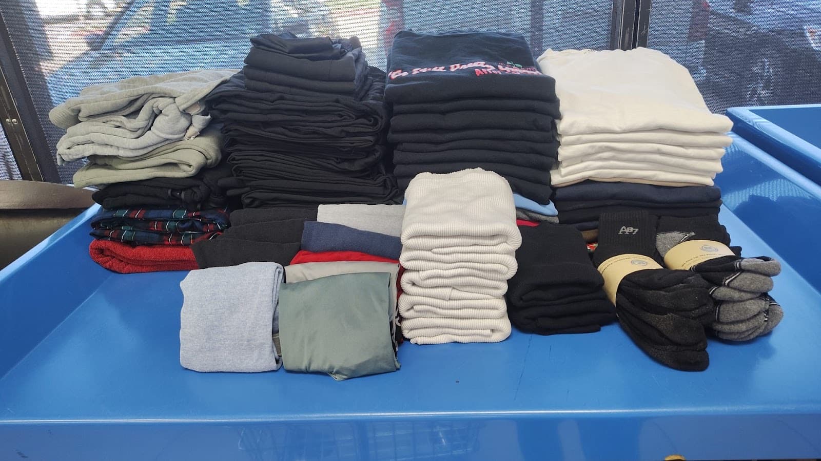 Folded clothes sorted by color, including socks, tees, and sweatshirts