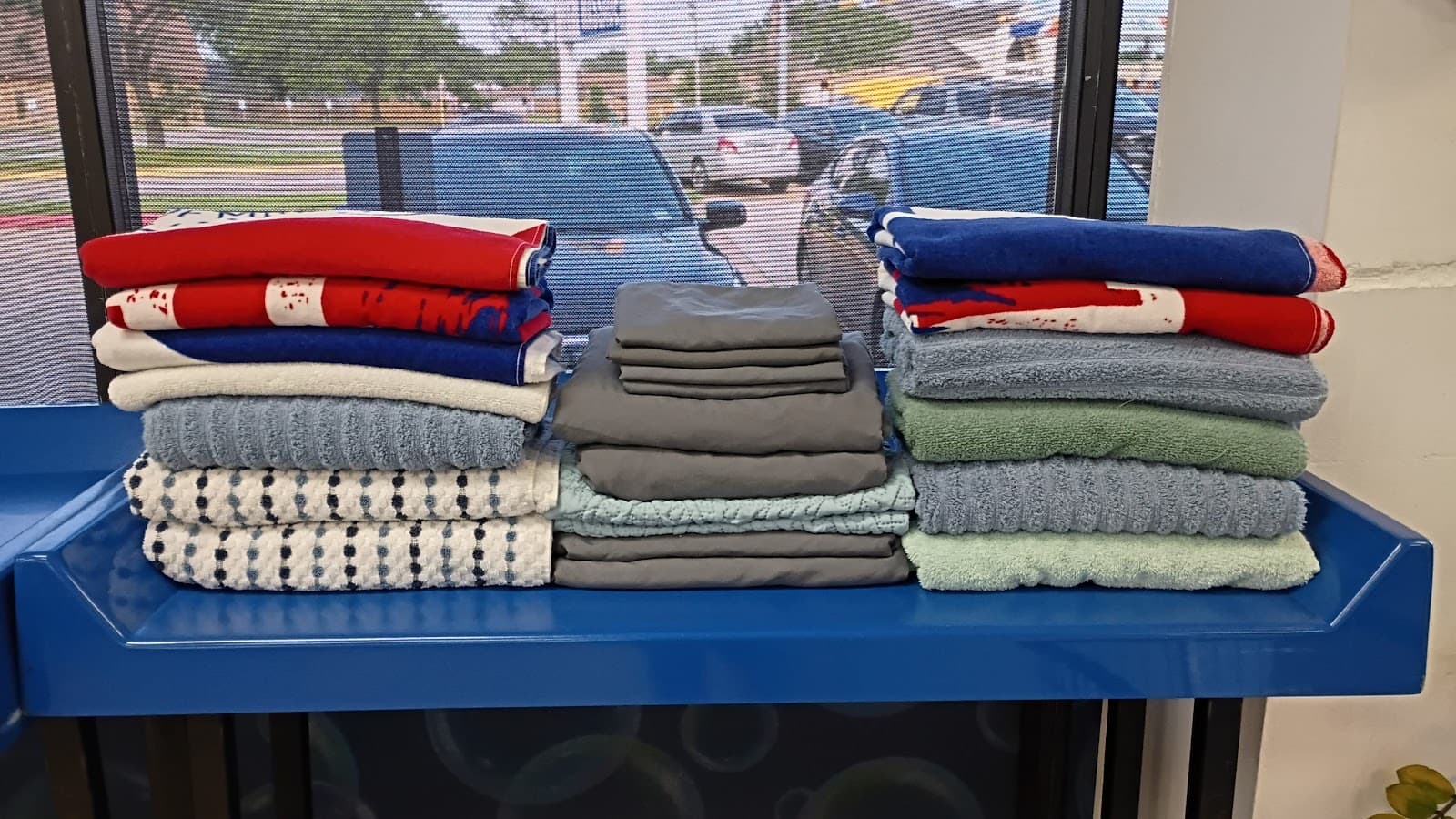 Neatly folded towels and linens stacked by color, ready for a commercial delivery