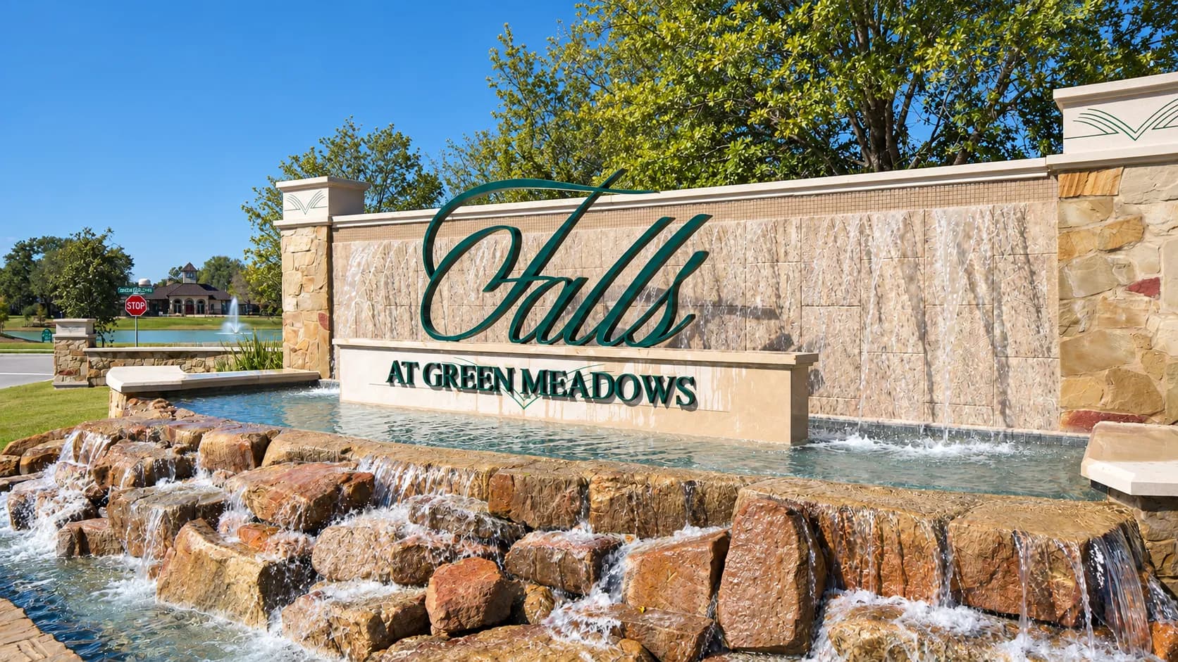 Falls at Green Meadows entrance monument sign with a stone waterfall feature