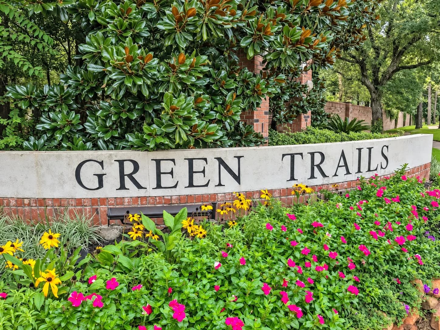 Green Trails community entrance monument sign surrounded by flowering shrubs and mature trees