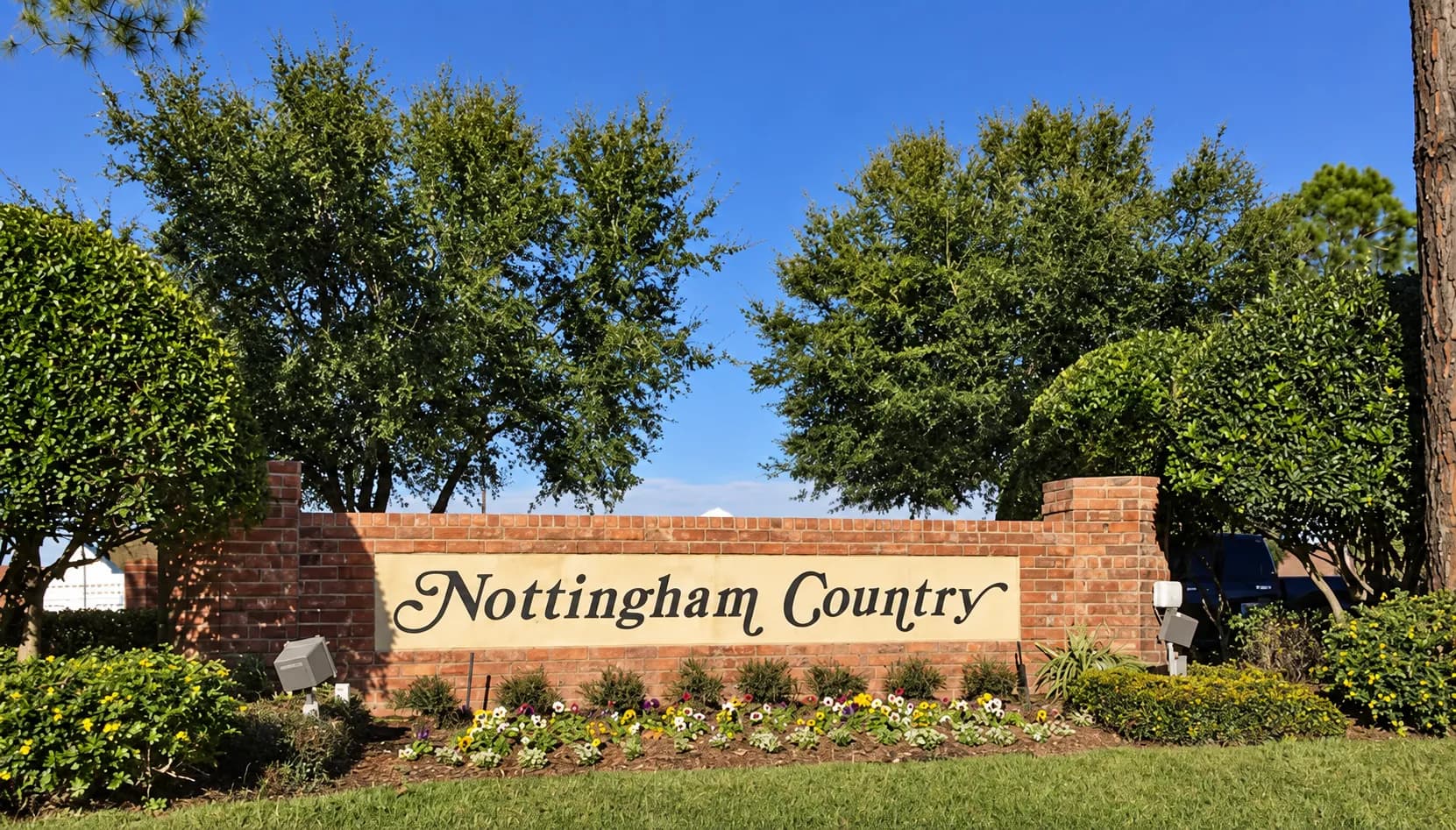 Nottingham Country brick entrance monument sign framed by mature oak trees